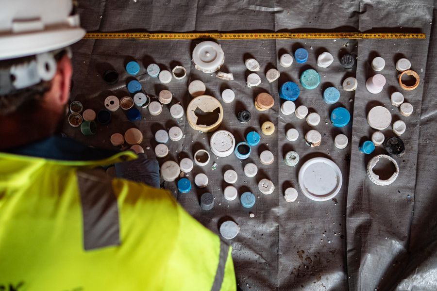 Plastic bottle caps lined up by crew members offshore during cleanup