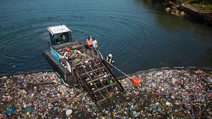 Interceptor Tender in Jamaica, removing trash from a barrier at the mouth of a gully.